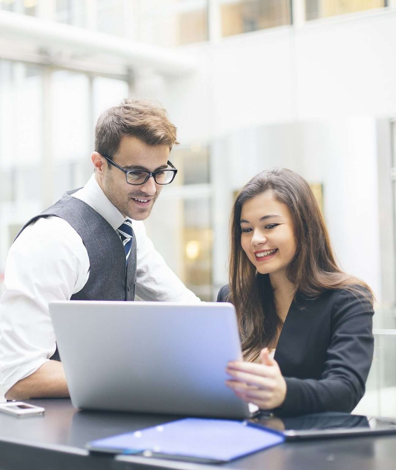 Business colleagues smiling while reviewing laptop together
