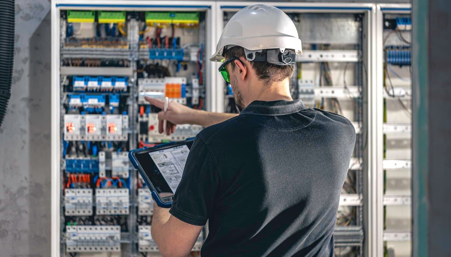 Electrician inspecting electrical control panel using tablet